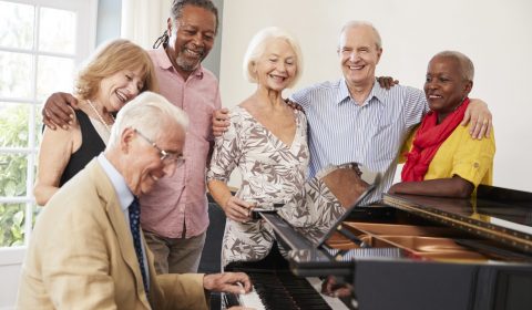 Group Of Seniors Standing By Piano And Singing Together